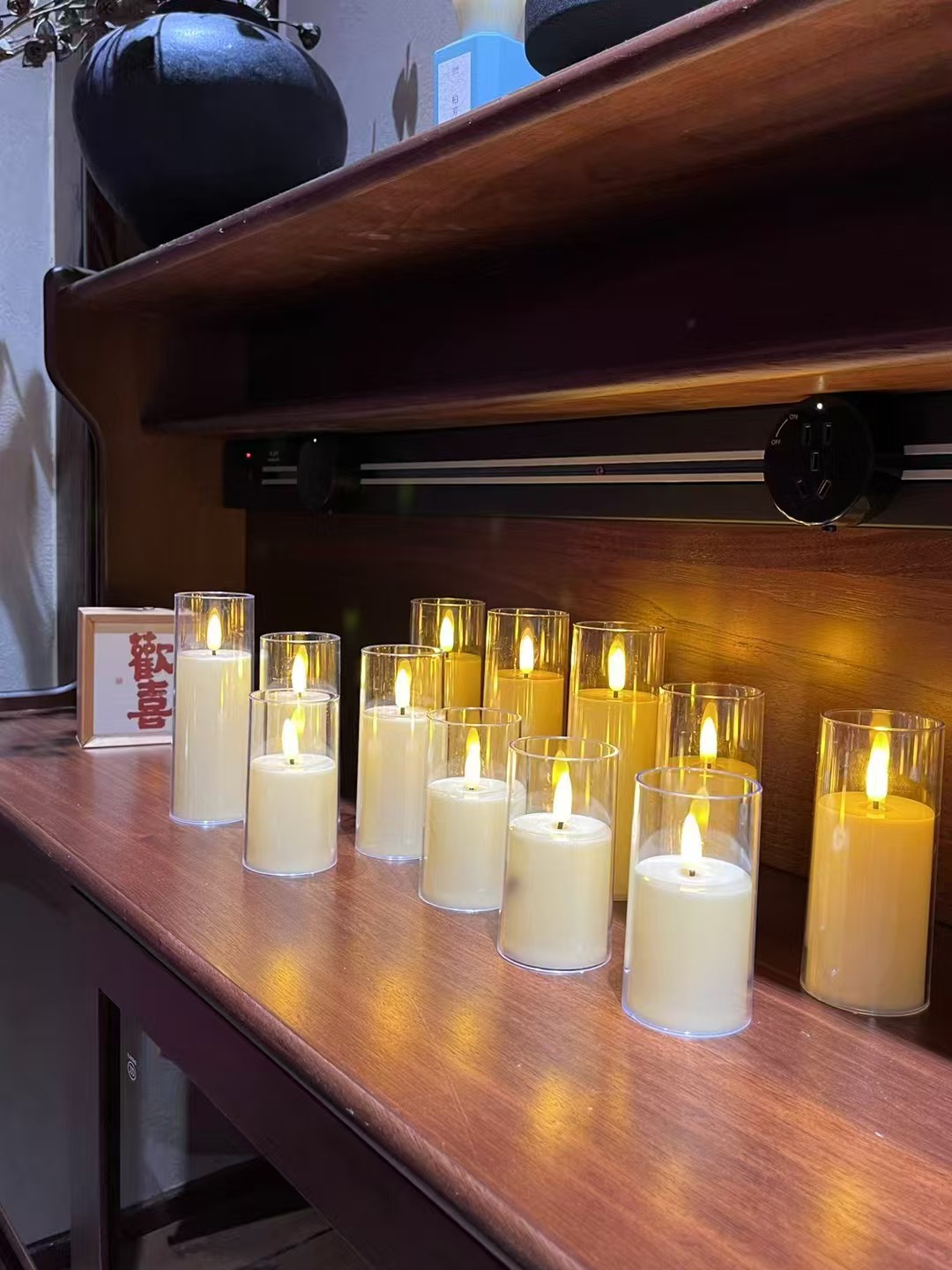 Glass-enclosed LED candles in mixed heights illuminating a wooden shelf