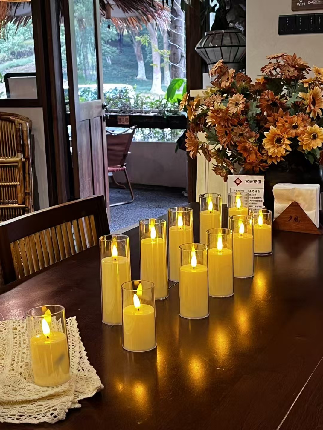 Warm glass-enclosed LED pillar candles on a café table beside autumn-coloured flowers
